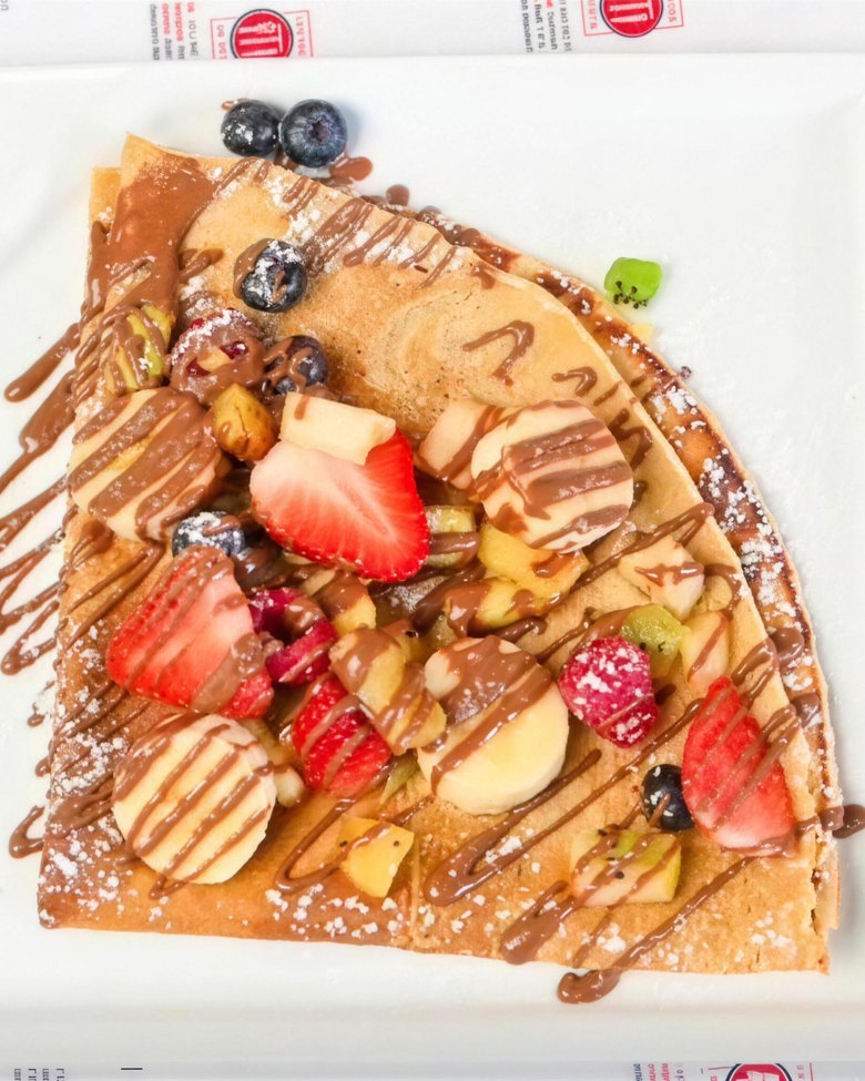 Crêpe pliée aux fraises, banane et fruits rouges, nappée de chocolat